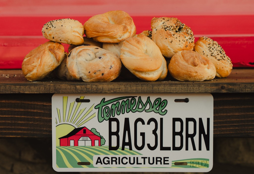 Assorted bagels on a rustic shelf with a Tennessee Bagel Barn style license plate